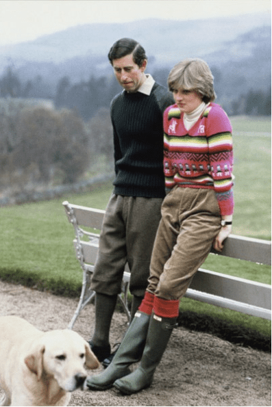 Princess Diana wearing a brightly patterned jumper with corduroy trousers and wellington boots while Prince Charles wearing black jumper, dark gray trousers, and shoes