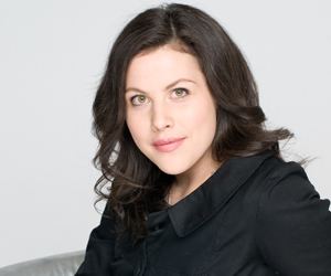 Sofie Allsopp smiling, with wavy black hair, and wearing a black blouse.