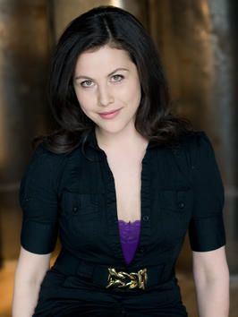 Sofie Allsopp smiling, with wavy black hair, and wearing a black blazer over a purple shirt.