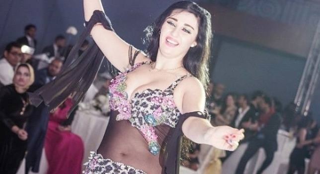 Sofinar Gourian smiling while dancing and wearing a black floral belly dance costume