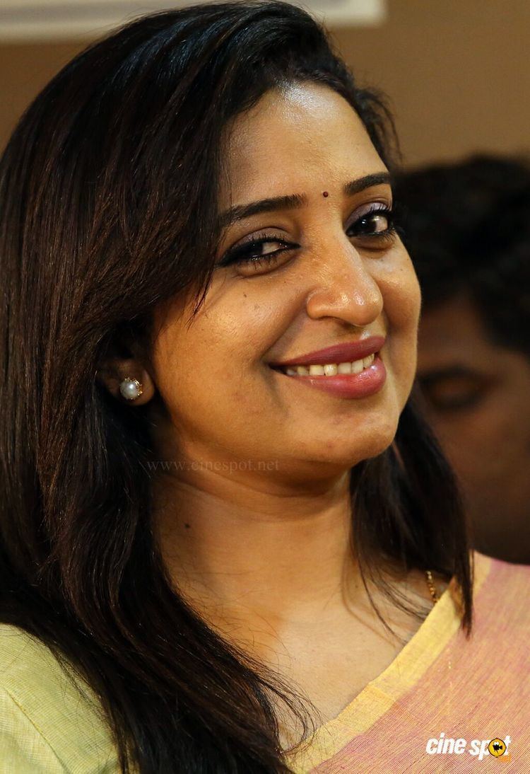 Sona Nair smiling and wearing earrings.