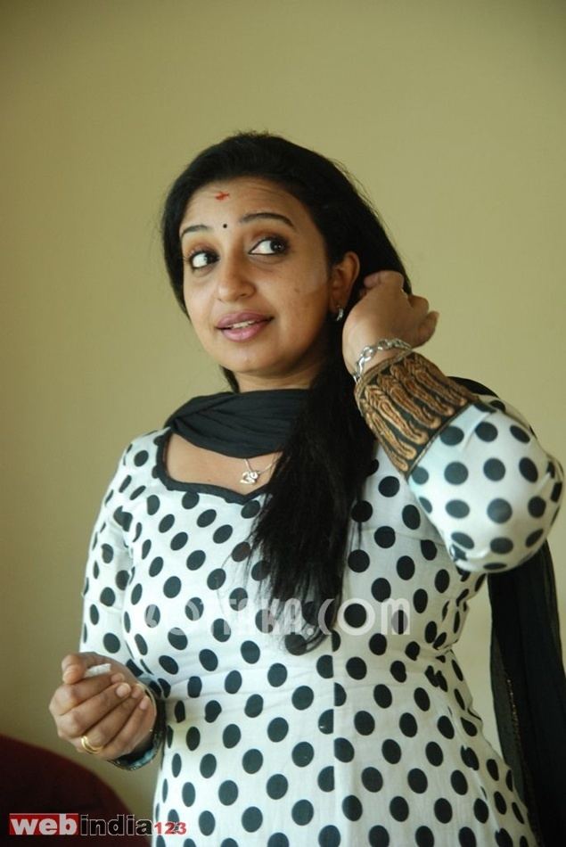 Sona Nair wearing earrings, a bracelet, a black scarf, and a black and white polka dot dress.