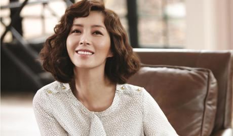 Song Yoon-ah smiling with short curly hair while wearing a white blouse