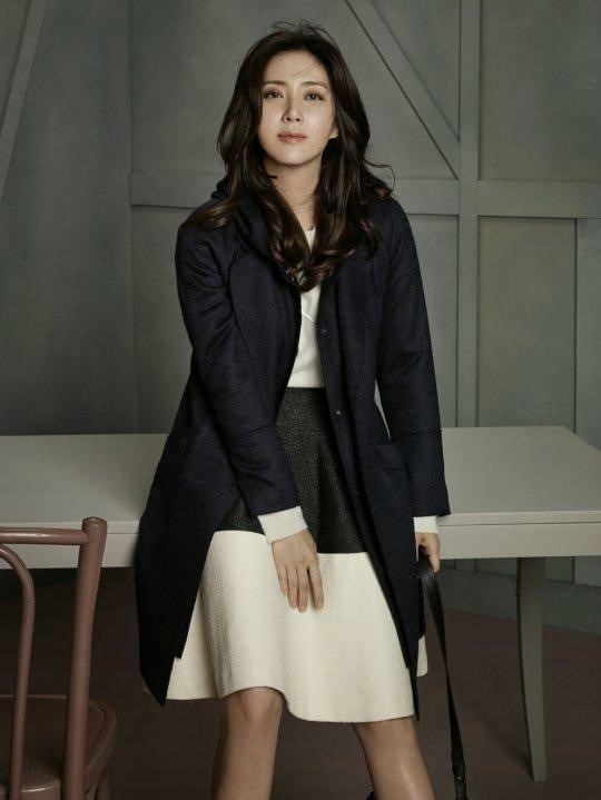 Song Yoon-ah leaning on the table while wearing a black coat and a black and cream dress