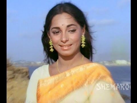 Sonia Sahni smile, wearing earrings and a yellow dress.