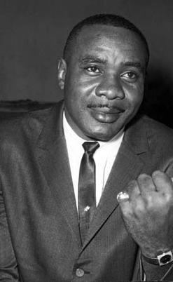 Sonny Liston smiling and wearing coat, long sleeves and neck tie