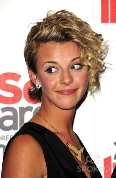 Sophia Di Martino smiling and wearing black dress, necklace and earrings