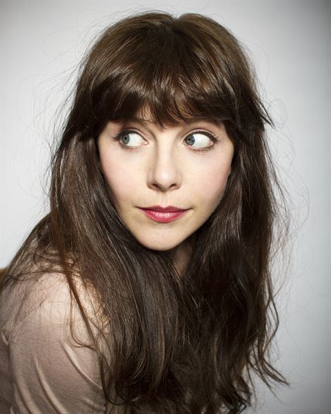 Sophia Di Martino looking at her side while wearing brown blouse