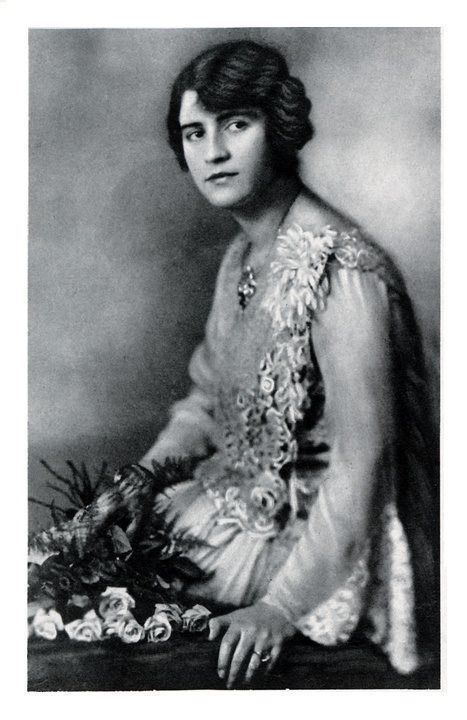 Soraya Tarzi looking serious in a dress while holding some flowers