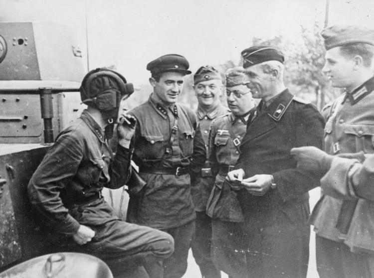 Several German soldiers are gathered around a tank, socializing and smoking. The soldiers were stationed at the German Russian border in c1939. All are wearing army unifroms.