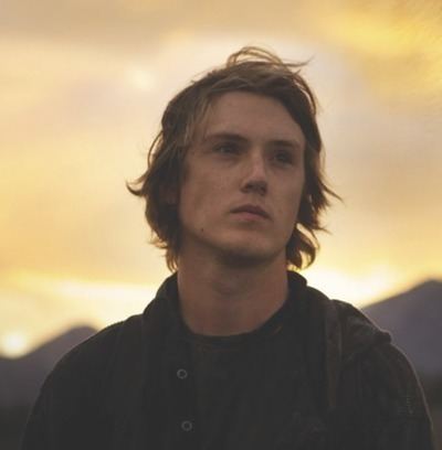 Spencer Treat Clark looking afar while wearing a black jacket and black t-shirt in the 2014 film, Druid Peak