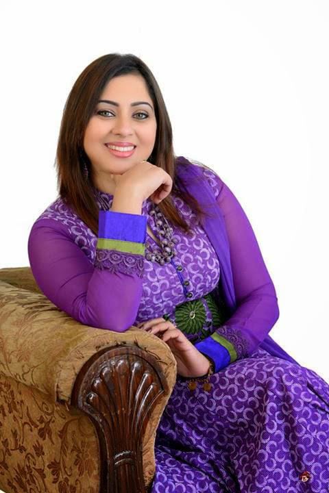Sreeya Remesh smiling while sitting on a couch with her right hand on her chin, she has a black hair wearing dangling earrings, a necklace, bracelet, and purple dress