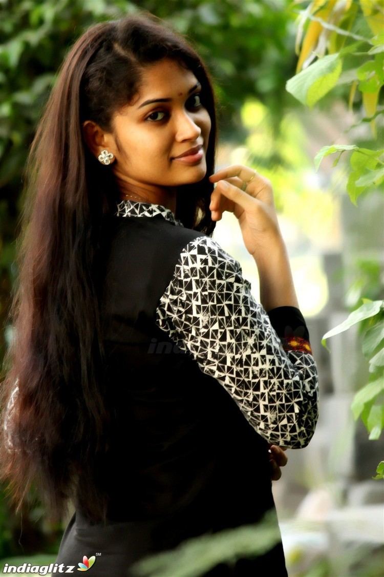 Sri Priyanka smiling while wearing a black and white long sleeve dress and earrings