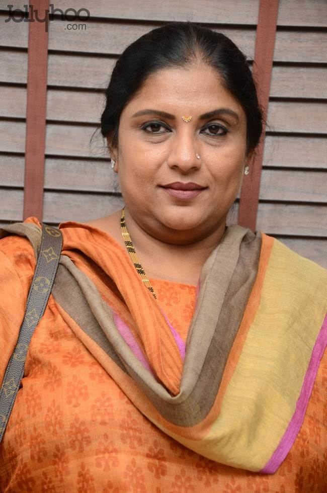 Sripriya wearing an orange dress while carrying a Louis Vuitton bag