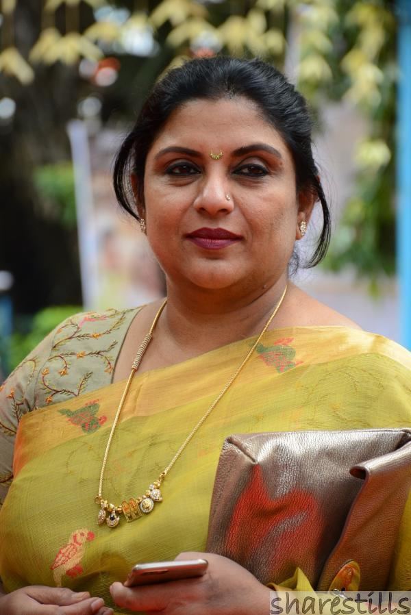 Sripriya in her yellow Indian dress holding her phone and purse
