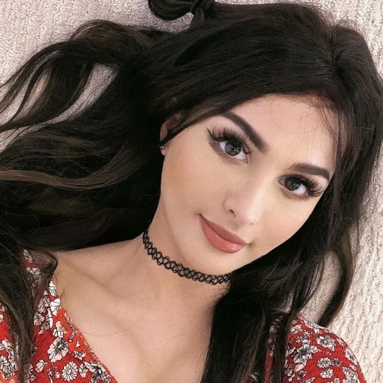 Alia Shelesh popularly known as SSSniperWolf, a popular gamer and YouTube personality, smiling, with long black hair, wearing a black choker and a red floral top.