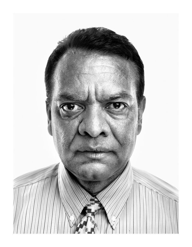 Stanley Praimnath posing closer with facial wrinkles visible and wearing a white striped polo shirt and tie.