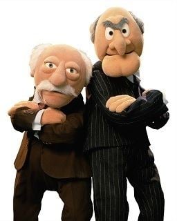 Statler wearing a brown suit and Waldorf wearing a black suit, a pair of Muppet characters best known for their cantankerous opinions and shared penchant for heckling.