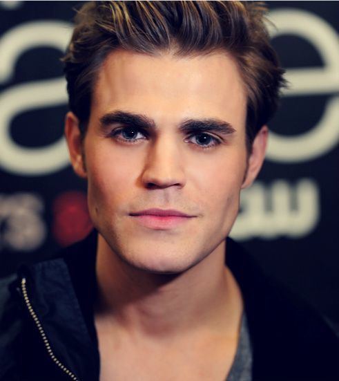 Stefan Salvatore  with a tight-lipped smile, spiked brown hairs, wearing a grey t-shirt under a black zipper