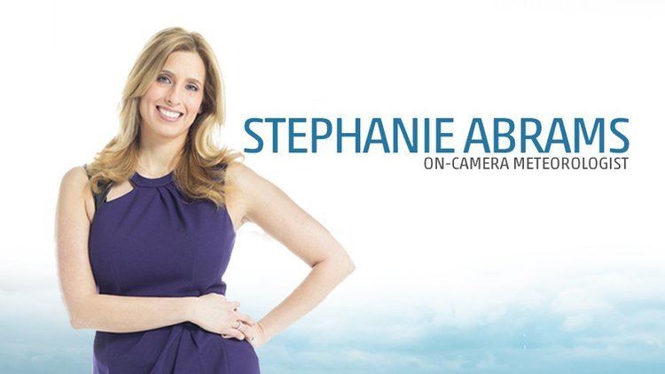 Poster of Stephanie Abrams smiling while hands on her waist, with blonde hair, and wearing a violet sleeveless dress.