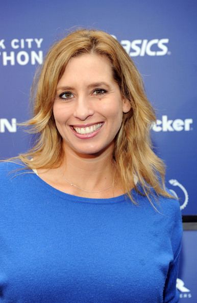 Stephanie Abrams smiling, with blonde hair, and wearing a blue shirt.