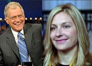 David Letterman and Stephanie Birkitt are smiling (from left to right). David with white hair is wearing eyeglasses, a blue striped necktie with a microphone, wearing a white collared shirt, and a pinstriped suit. Stephanie with blonde wavy hair is wearing a black shirt.