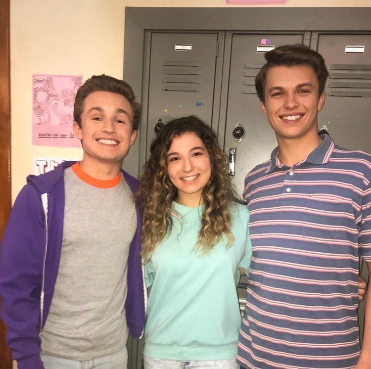 Stephanie Katherine Grant, Zayne Emory, and Jacob Hopkins are smiling. Stephanie with curly hair and wearing a mint green blouse, Zayne wearing a purple jacket and Jacob wearing a striped polo shirt.