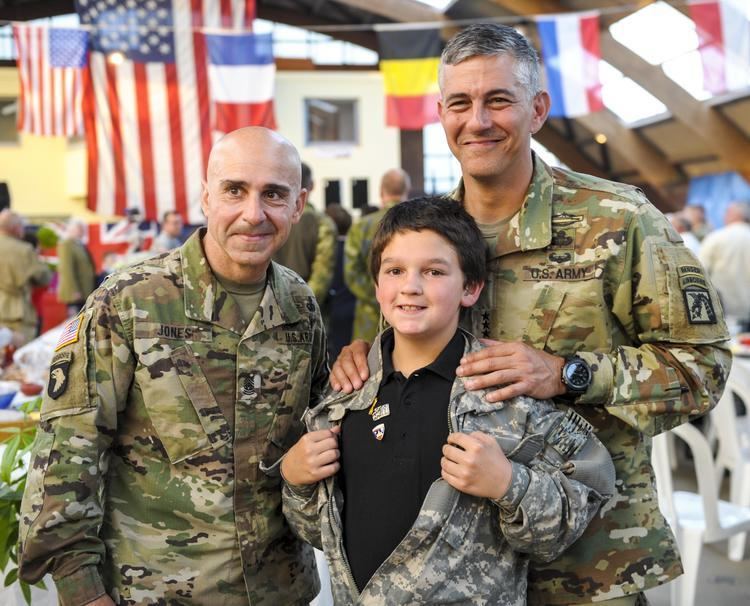 U.S. Army Lt. Gen. Stephen J. Townsend (right), commanding general of the 18th Airborne Corps, and Command Sgt. Maj. Benjamin Jones (left), 18th Airborne Corps, poses for a photo with a French child during the Liberty Banquet in Sainte Mere Eglise, France, on June 4, 2016.