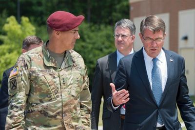 Stephen J. Townsend wearing a red cap and army uniform while talking with a gentleman wearing a suit and tie.