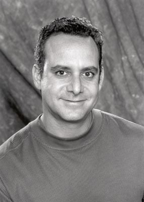 Steven G. Kaplan with a tight-lipped smile while wearing t-shirt