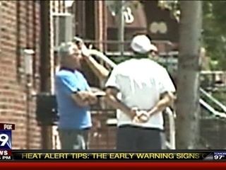 Steven Mazzone with his arms crossed his chest and wearing a blue shirt with a man wearing a white cap and shirt.