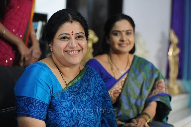 Sudha smiling and wearing blue dress and the woman beside her wearing blue and green dress