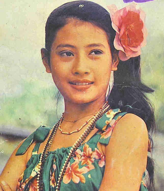 Young Sujarinee Vivacharawongse wearing floral dress, necklaces and a flower on her hair