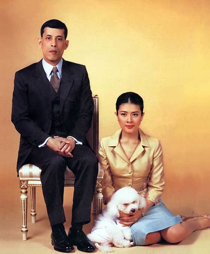 Sujarinee Vivacharawongse wearing gold long sleeves and blue skirt with their dog while Prince Maha Vajiralongkorn wearing black coat, white long sleeves and brown neck tie