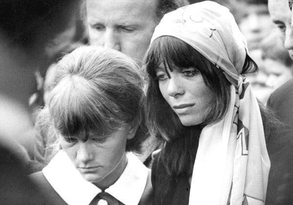 Suki Potier together with Barbara Jones crying at the funeral of Brian Jones wearing a black dress and a white handkerchief on her head.
