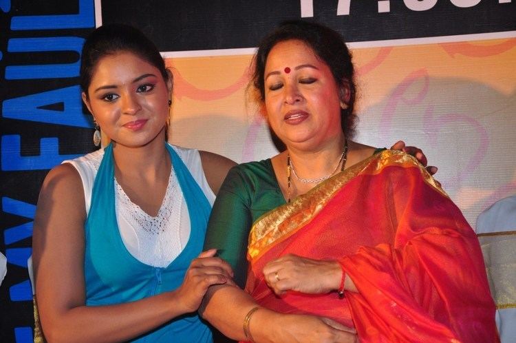 Nakshatra smiling and wearing a blue top and white inner top while  her mother Sumithra wearing a green blouse and red and gold dupatta