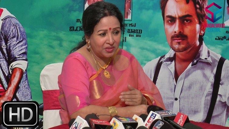 Sumithra at the press conference wearing a pink dress, pink dupatta, gold necklace, earrings, and bracelet