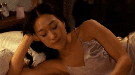 Kim Ji-hyun lying on the bed while wearing pink silk sleepwear in a movie scene from the 2001 film Summertime