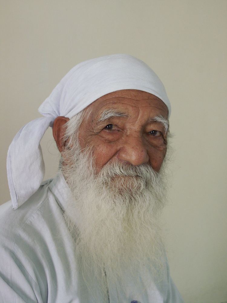 Sunderlal Bahuguna with a white long mustache and beard, wearing a white bandana and a white shirt.