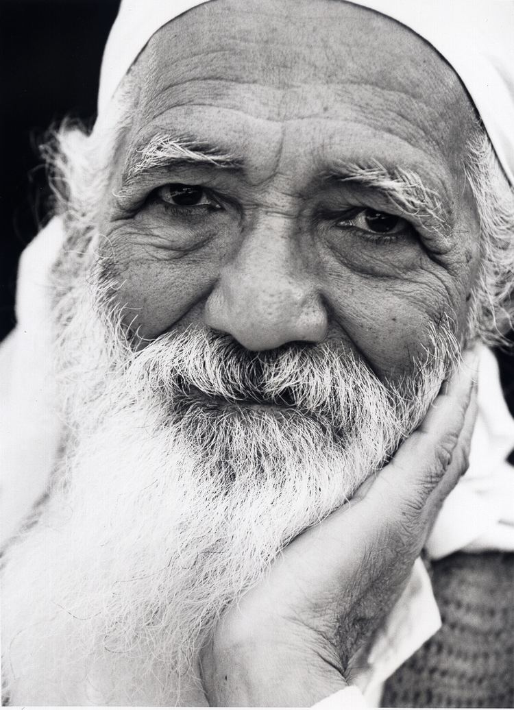 Sunderlal Bahuguna with white mustache and beard, wearing a white bandana while leaning one side of his face against his fist.