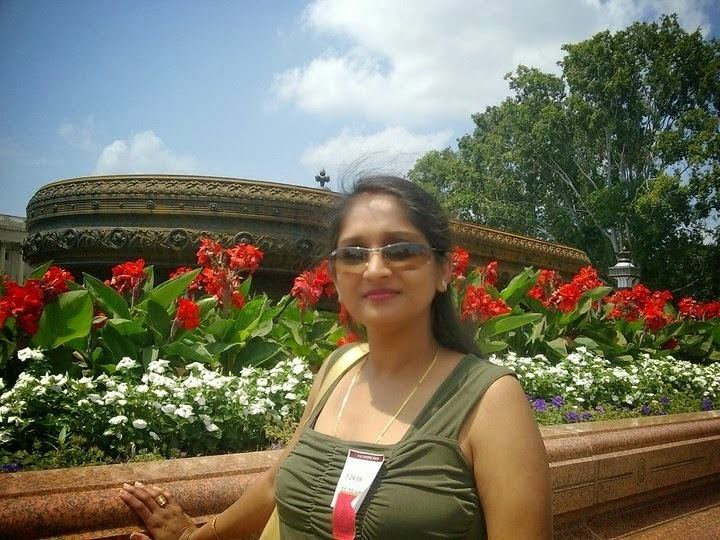 Sunitha wearing eyeglasses with beautiful flowers in the background.