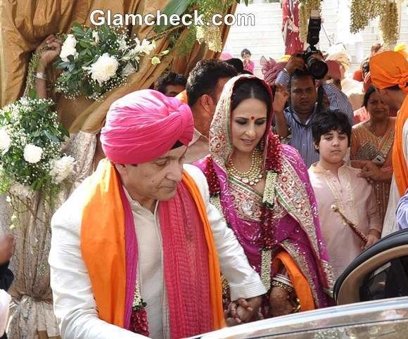 Surendra Hiranandani with wife Alka Bhatia at their wedding. Surendra wearing a pink turban, white robe, and a pink and orange scarf while Alka wearing a colorful traditional Indian dress.