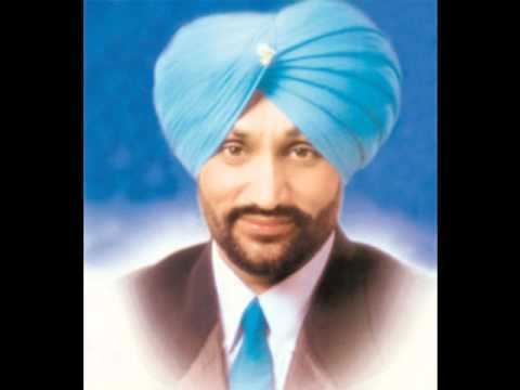 Surjit Bindrakhia smiling and wearing a white sleeve, black suit, blue necktie, and blue turban in a blue background