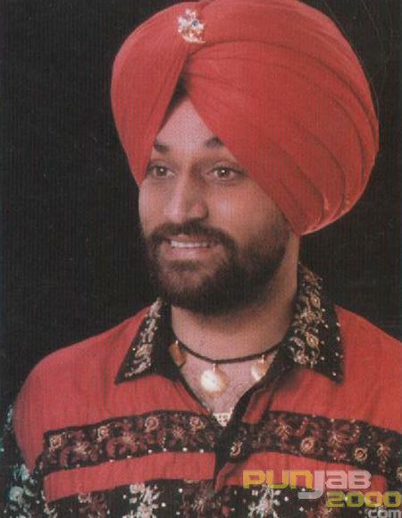Surjit Bindrakhia smiling with a mustache and beard and wearing a black and red shirt, a necklace, and a red turban on a black background