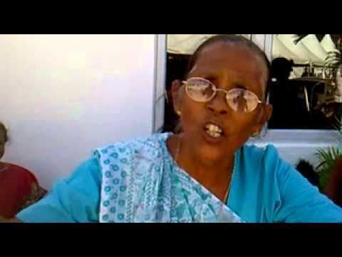 Sushil Ramgoolam wearing eyeglasses, earrings, a necklace, and a blue dress.