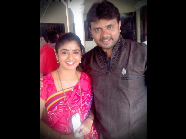 Sushma K. Rao smiling and wearing a pink dress with her husband Preetham Gubbi also smiling and wearing a gray shirt.