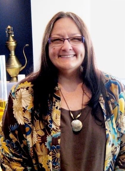 Suzan Shown Harjo wearing eyeglasses, necklace, brown inner top and brown and cream floral coat with touch of color blue