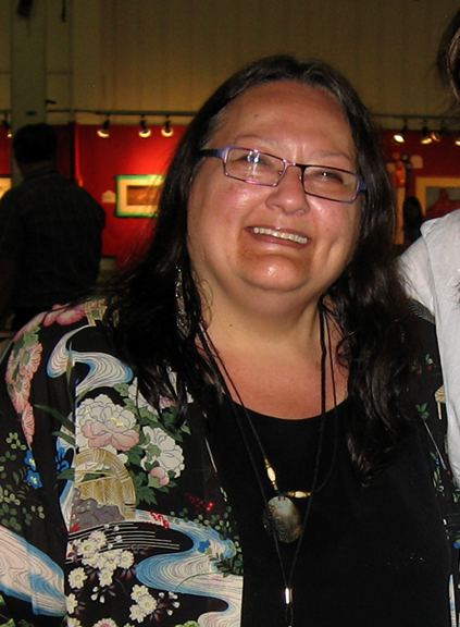 Suzan Shown Harjo wearing eyeglasses, necklace, black inner top and colorful coat