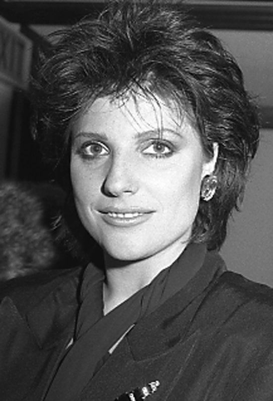 Suzanne Danielle smiling while wearing a scarf, blouse, and earrings