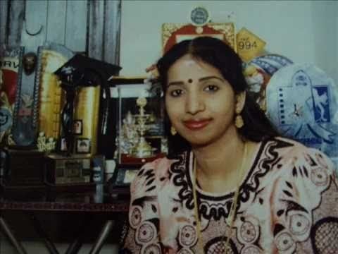 Swarnalatha's tight lipped smile while wearing brown and cream dress and gold jewelries